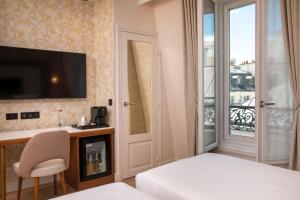 um quarto de hotel com uma cama, uma secretária e uma janela em Hôtel des Champs-Elysées em Paris