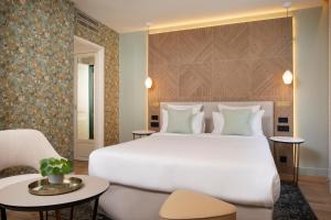 a bedroom with a large white bed and a chair at Hôtel des Champs-Elysées in Paris