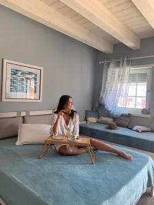 a woman sitting on a bed with a table at Laura e Christian - Rooms in Grado