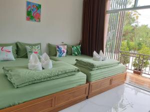 two twin beds in a room with a window at บ้านสวนนิสา in Sattahip