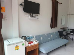 a blue couch in a room with a tv and a refrigerator at บ้านสวนนิสา in Sattahip