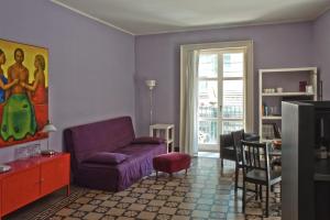 sala de estar con sofá púrpura y ventana en Tre Vie apARTment con terrazzo giardino pensile, en Catania