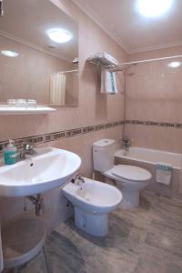 uma casa de banho com 2 lavatórios, um WC e uma banheira em Hotel Castilla em Gijón