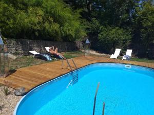 une personne se pose dans une chaise à côté d'une piscine dans l'établissement Le CLOS BOURBON, à Ferrières-sur-Sichon