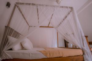 ウェリガマにあるParadise Bungalowのベッドルーム(白いカーテン付きの天蓋付きベッド1台付)