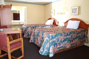 a hotel room with two beds and a desk at Claremore Motor Inn in Claremore
