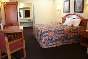 a hotel room with a bed and a desk and a chair at Claremore Motor Inn in Claremore