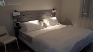 Cette chambre comprend un lit avec des oreillers blancs et une chaise. dans l'établissement Calme et Central à Jonzac, à Jonzac