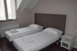 2 camas en una habitación pequeña con sábanas blancas en B&B Leonardo, en Rho