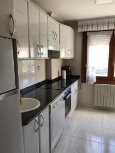 una cocina con armarios blancos y fregadero. en La Cabañita de Leiva, en Leiva
