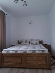 ein Schlafzimmer mit einem großen Bett mit einem Holzrahmen in der Unterkunft Casa Corina in Călimăneşti