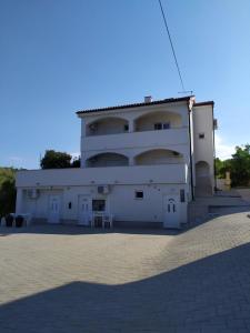 a large white building with a table in front of it at Apartmani Milenij in Rab