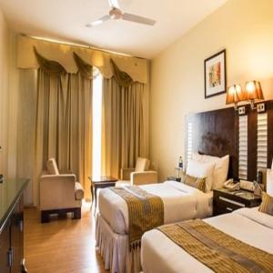 a hotel room with two beds and a chair at The Red Maple Mashal in Indore