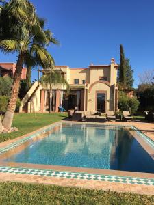 a swimming pool in front of a house at Villa entière GOLF MARRAKECH in Marrakesh