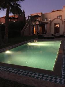 a swimming pool in front of a house at Villa entière GOLF MARRAKECH in Marrakesh