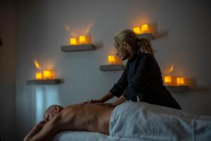 Uma mulher está a fazer uma massagem a um homem. em Hotell Rusthållargården em Arild
