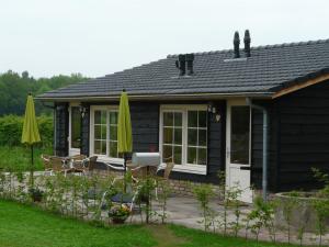 a small black cottage with a patio and chairs at Erve Dikkeboer in Bathmen