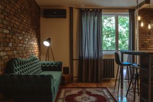 een woonkamer met een groene bank en een bakstenen muur bij Loft Apartman Menhetn in Šabac