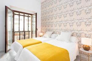 een slaapkamer met 2 bedden met gele en witte lakens bij Genteel Home Amor de Dios in Sevilla