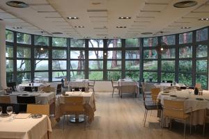 Augusta Barcelona Vallès في جرانويرس: مطعم بطاولات بيضاء وكراسي ونوافذ كبيرة