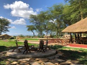a patio with chairs and a table and a picnic shelter at Africa Safari Lake Manyara located inside a wildlife park in Mto wa Mbu