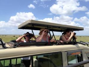 een groep mensen die foto's nemen op het dak van een voertuig bij Teen Ranch Kenya in Amboseli