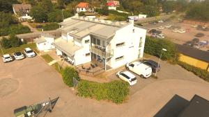 a white house with cars parked in a parking lot at Staylong Hotell in Täby