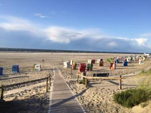 a beach with many trash cans and a wooden boardwalk at Haus Achterum in Langeoog