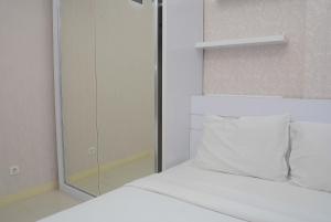 a white bed with a glass shower in a room at Comfortable 2BR Green Pramuka City Apartment By Travelio in Jakarta