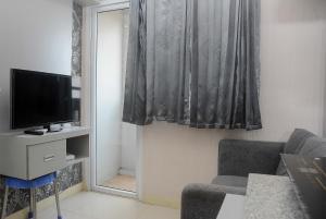 a living room with a couch and a tv and a window at Comfortable 2BR Green Pramuka City Apartment By Travelio in Jakarta
