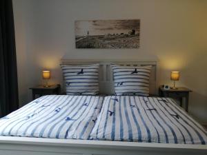een bed met blauwe en witte gestreepte lakens en twee lampen bij Steinmarner Bude 2 in Cuxhaven