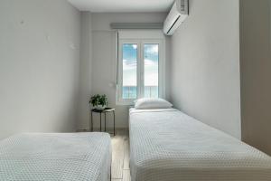 two beds in a room with a window at MG Villas & Suites in Paleo Tsifliki