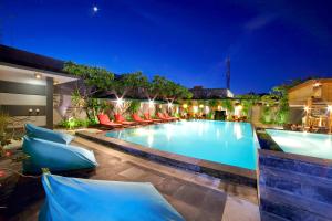a swimming pool at night with chairs around it at The Banyumas Villa in Denpasar