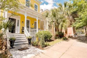 a yellow house with palm trees in front of it at 111 Waldburg street Beautifully Renovated Historic 5 bedroom 5 bath in Savannah