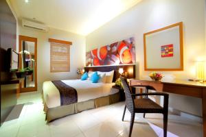 een slaapkamer met een bed, een bureau en een stoel bij The Banyumas Villa in Denpasar