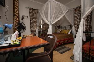 Schlafzimmer mit einem Bett und einem Schreibtisch mit einem Tisch in der Unterkunft Korona House Hotel in Arusha