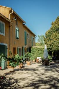 een patio met een parasol en stoelen en een gebouw bij Le Mas de Trévouse in Saint-Saturnin-lès-Avignon