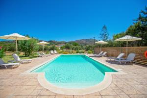 a swimming pool with chairs and umbrellas at Elegant Maisonettes Kalamaki in Kalamaki