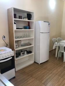 uma cozinha com um frigorífico branco e uma mesa em Constancy residence em Itarema