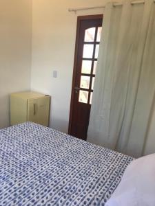 um quarto com uma cama e uma porta com uma janela em Constancy residence em Itarema