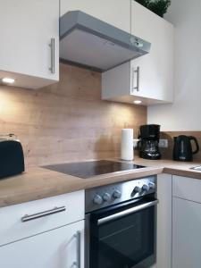 een keuken met witte kasten en een kookplaat oven bij Steinmarner Bude 2 in Cuxhaven
