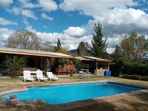 een achtertuin met een zwembad en een huis met een tafel en stoelen bij Cabaña Campestre de 1 Ambiente En Paine in Paine