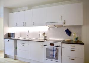 Una cocina blanca con gabinetes blancos y un fregadero. en Modern apartment, en Svolvær