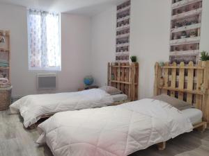 two beds in a room with white walls at Gîte proche du canal du midi et Narbonne 2 chambres in Mirepeisset