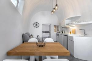 a kitchen with a wooden table and white cabinets at I-Sol in Akrotiri