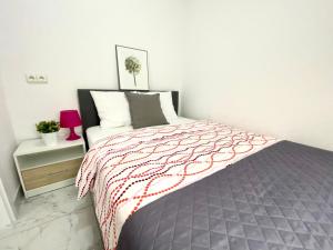 a bedroom with a bed with a red and gray blanket at Center Warsaw - Apartmenty Jana Pawła II in Warsaw