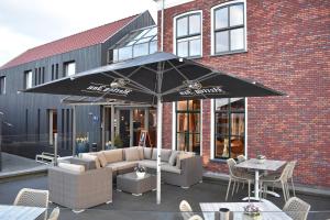 a patio with a couch and an umbrella in front of a building at Hotel-Restaurant Termunterzijl in Termunterzijl