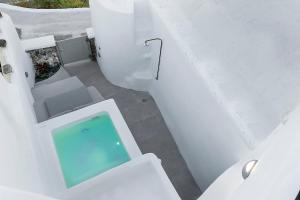 a white bathroom with a swimming pool in it at Antron Cave House in Akrotiri