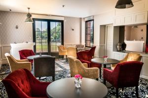 a waiting room with tables and chairs and windows at Les Jardins de Joséphine - Le Manoir in Évreux