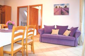 ein Wohnzimmer mit einem lila Sofa und einem Tisch in der Unterkunft Apartamenty Dom na Wzgórzu Gardenia in Stronie Śląskie